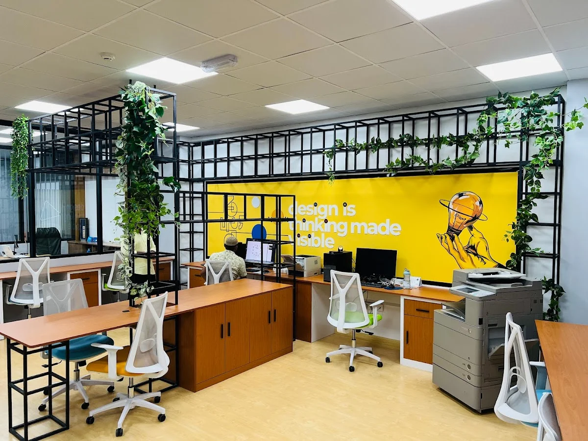 Open-plan graphic design studio with computer workstations, color printers, and material sample displays for client projects